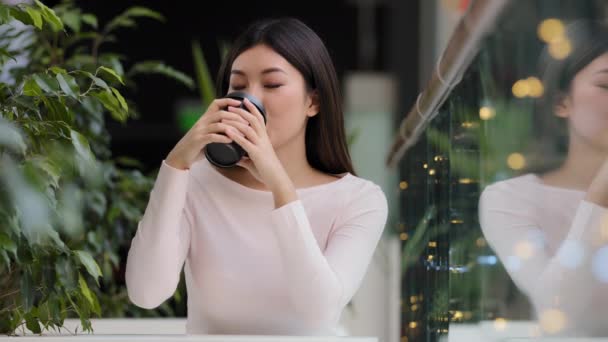 Azji dziewczyna uśmiech ciesząc się picia pachnące pyszne kawa gorąca herbata rano cappuccino w kawiarni siedzi przy stole uśmiechnięty czekając na spotkanie relaks na przerwie odpoczynku w stołówce weekend — Wideo stockowe