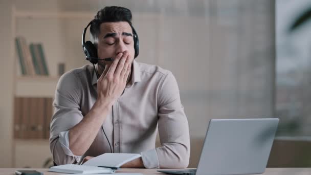 Senny młody arabski człowiek nudne facet pracownik operator w słuchawki z mikrofonem patrząc na laptop ekranu pracy w usługi wsparcia klientów zmęczony mężczyzna pracownik ziewanie wyczerpany pracoholik biorąc drzemkę — Wideo stockowe