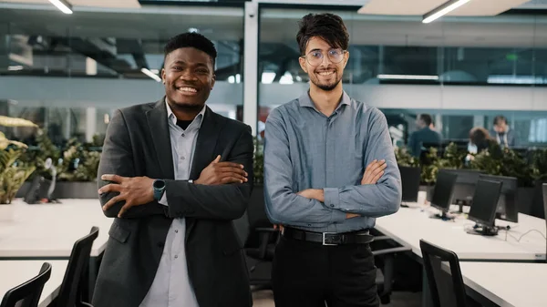 Multiraciale paar collega 's uit het bedrijfsleven glimlachen diverse collega' s Arabisch jongeman Afrikaans manager zakenman man staan binnen samen poseren kruisen armen kijken naar camera op kantoor — Stockfoto