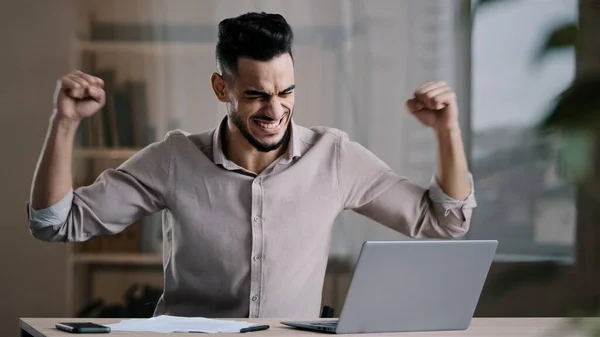 Young successful joyful hispanic man male investor businessman hold document look at laptop win online lottery celebrate victory get new distance job opportunity rejoice read good news feel motivation — Stock Photo, Image