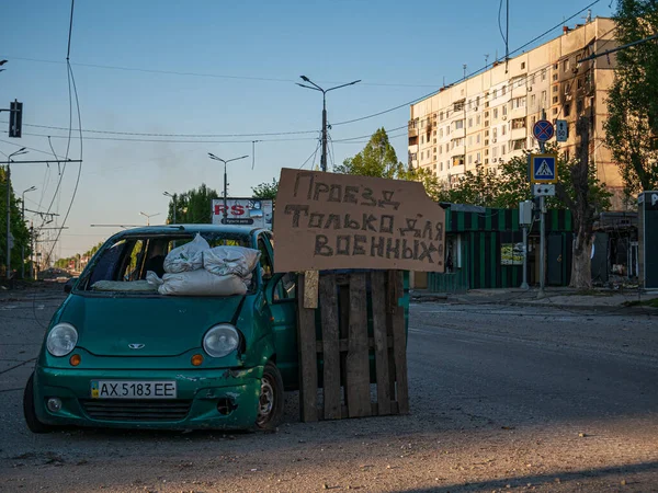 Харьков, Харьков, Украина - 05.07.2022: разбитая машина уничтожила автомобиль на пустой улице города после бомбардировки города разрушения войны знак дороги только для военных вторжений оккупационной войны России — стоковое фото