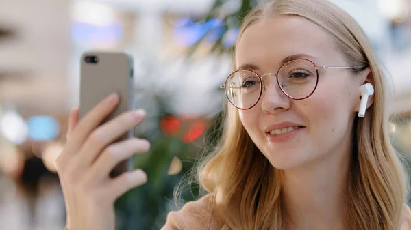 Close-up side view caucasian woman girl blogger wears wireless headphones online channel video call conference remote chat conversation with friends using smartphone mobile app talking to phone camera — Foto Stock