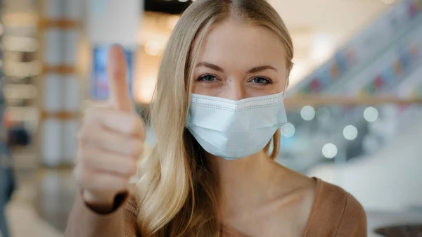 Indoors portrait caucasian woman patient girl female lady in face protective medical mask protecting health from coronavirus infection covid shows like puts thumbs up recommends wearing respirator — 图库照片