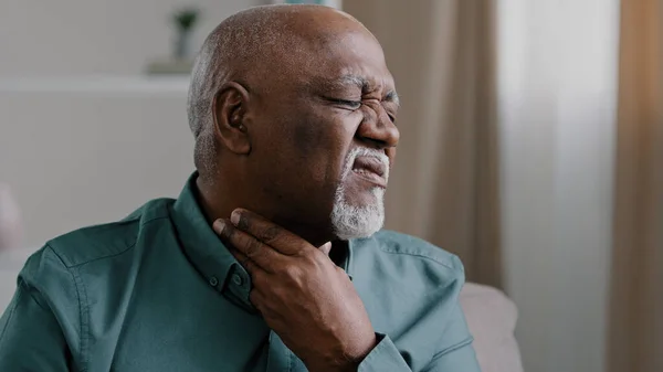 Sick African old man suffer from sore throat painful tonsillitis irritation senior male indoor check gland laryngitis bacterial infections diseases pain in neck severe ache cervical osteochondrosis — Stok fotoğraf