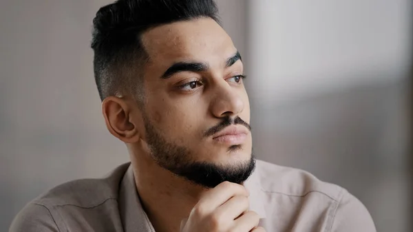 Pondering serious young arabian man businessman male student sit at home office hold hand on chin lost in thoughts dreamy looking away consider market risks make difficult decision generate new ideas —  Fotos de Stock