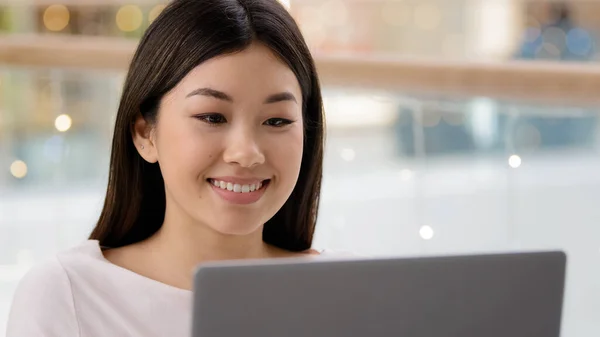 Porträtt leende glad asiatisk kvinnlig ansikte tittar på bärbar dator nöjd flicka kvinna frilansare chef arbetare chef skriva dator med hjälp av shopping app-tjänst titta på video på nätet på webbplats surfning nätet — Stockfoto