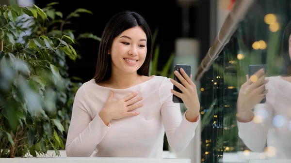 Asiatico coreano amichevole ragazza giapponese signora cinese femmina sorridente salutando telefono webcam donna con gadget mobile parlando fare videochiamata in cafe ufficio tavolo chatta da virtuale conferenza app — Foto Stock