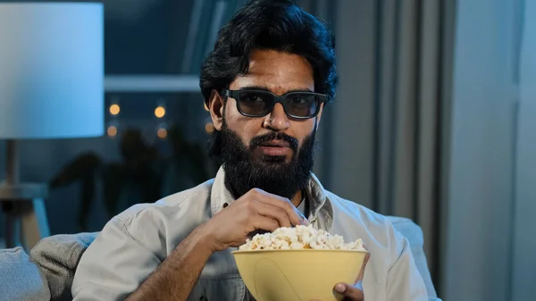 Portrait arabic hispanic latino indian muslim bearded man in 3d glasses watching TV relaxed guy in virtual eyeglasses enjoying movie program online eating crunchy popcorn at home in evening night dark — Stock Photo, Image