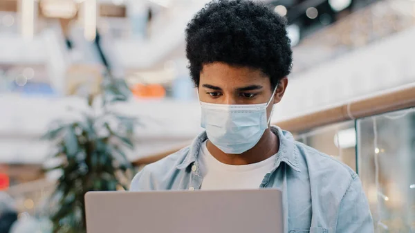 Retrato afro-americano cara estudante usuário homem de negócios em máscara médica pensando plano cria estratégia ideia trabalhando com laptop pensativo ponderando resolver problema com aplicativo de computador pensa — Fotografia de Stock