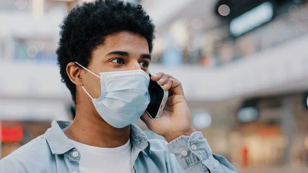 Крупным планом афроамериканец в защитной маске говорит по мобильному телефону отвечая на звонки говорит доктору удаленно жалуясь на коронавирусные симптомы деловой разговор со смартфоном — стоковое фото