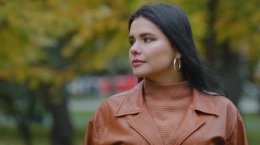 Kadın portresi yakın plan başarılı ciddi iş kadını kameraya bakar çekici İspanyol kadın esmer sonbahar parkında duruyor dalgın milenyum bayan modellik yapıyor