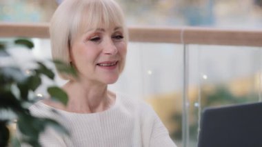 Kendine güvenen olgun iş kadını dizüstü bilgisayarda yazıyor. İnternette çalışıyor. Yeni bilgisayar uygulamasından memnun.
