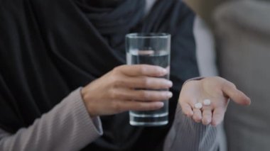 Kimliği belirsiz hasta Müslüman kadın tesettüre alındı. Kadın ellerinde baş ağrısı hapları var. Bir bardak mineral ferahlatıcı su.