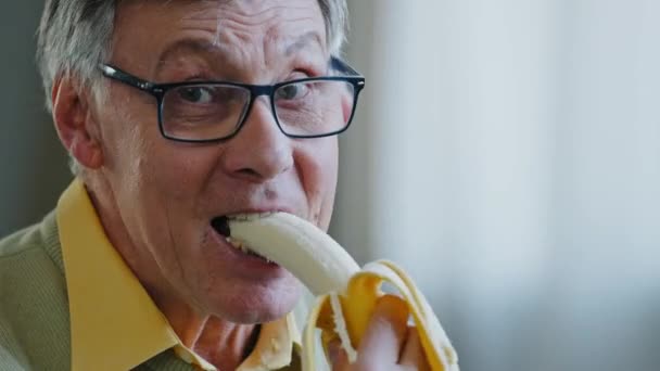 Close-up reifen alten 60ern männlichen Rentner Rentner älteren Großvater genießen Geschmack essen leckere gesunde Bananen weichen Früchten Gastritis Diät gute Gewohnheiten Ernährung Verdauungsprobleme Zähne Probleme — Stockvideo