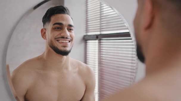Close up masculino reflexão no espelho bonito 30 anos unshaven confiante árabe indiano nu homem no banho sorrindo toothy sexy shirtless barbudo millennial hipster cara feliz sorriso se preparando para data — Vídeo de Stock