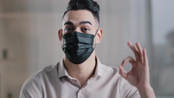 幸せなヒスパニック系男性従業員アラビア人男性起業家は、医療用マスクを着用すると、カメラを見てコロナウイルスの流行を防ぐことができます。 — ストック動画