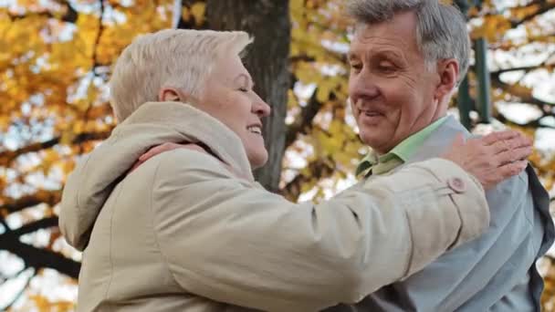 Sonbahar parkında yaşlı ve evli beyaz bir çifti sevmek olgun bir büyükanne gibi kucaklamak omuzlarında empati kurmak yaşlı büyükanne ve büyükbaba ile aile bağlarını kucaklamak. — Stok video