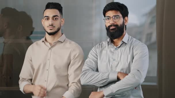 Two happy male colleagues multiracial diverse businesspeople partners men hispanic man arabian bearded guy smiling posing in office with crossed arms looking at camera confident corporate partnership — 비디오