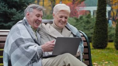 Yaşlı, mutlu, beyaz bir koca, olgun, yaşlı bir çift, büyük anne ve büyük baba, dizüstü bilgisayara bakar, iyi haber, internette komik videolar izler, internetten alışveriş yapar.