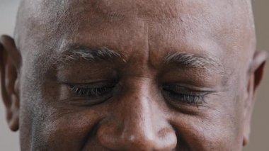 Kapalı Afrikalı yaşlı erkek gözleri kameraya bakıyor. Yaşlı, çift ırklı yaşlı, görme sorunu olan yaşlı bir adam. İyi görüş, lazer düzeltme, göz hekimliği, Alzheimer.