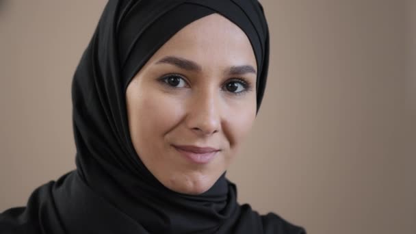 Närbild ansikte porträtt av unga vackra 30-talet muslimska islamiska arabiska kvinna modell bär traditionell hijab huvudduk säker poserar tittar på kameran dentala leende känsla väl nöjd med bra vision — Stockvideo