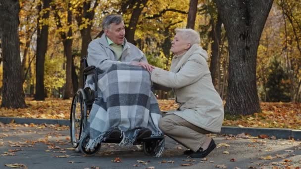 Caucasian female elderly grey-haired woman holding husband hand senior man with disability on wheelchair supporting old mature grandfather giving empathy care love married grandparents couple together — Stock Video
