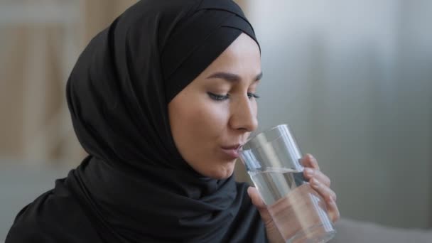 Gros plan arabique jeune femme avec la peau parfaite dans le hijab boire verre d'eau claire filtrée islamique jolie fille dégustation rafraîchissante liquide hydratant soif maintient l'humidité saine habitude — Video