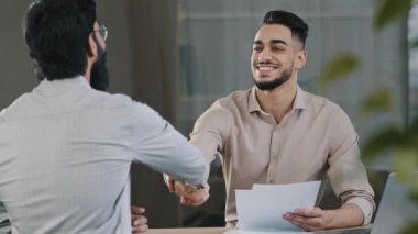 Two successful diverse business men colleague arabian salesman banker male manager shaking hand client customer accept common project successful corporate partnership deal agreement at office meeting