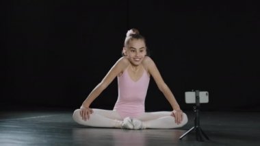 12 yaşındaki küçük kız çocuk balerin jimnastikçi akrobat. Kelebek pozu veriyor. Kalça kaslarını esnetiyor.