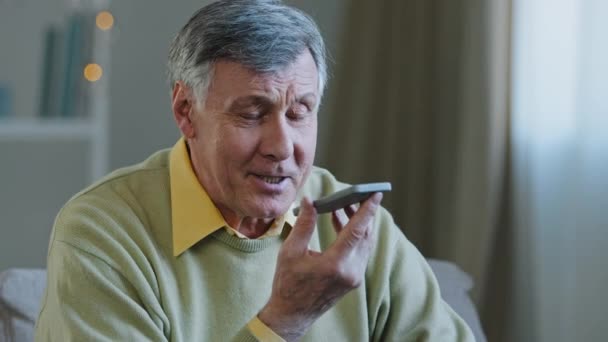 Ώριμος γκριζομάλλης 60s άντρας 70s ηλικιωμένος άνδρας στο σπίτι hold smartphone μιλήστε δυνατά στο τηλέφωνο μικρόφωνο ηχείο ηχητικό μήνυμα φωνής χρησιμοποιώντας μεγάφωνο μιλώντας με τα παιδιά απομακρυσμένη κινητή συνομιλία — Αρχείο Βίντεο