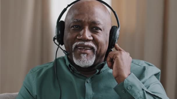 多明尼加60多岁的自由撰稿人商人，带着数字耳机上网与摄像机交谈，用电脑视频呼叫应用程序问问题，非洲年长的成熟男人祖父母在耳机里遥谈 — 图库视频影像