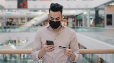 Medikal maskeli Hintli bir adam cep telefonu faturalarını internet üzerinden ödüyor. Cep telefonu siparişleri ile birlikte banka kartı numarası ödemesi yapıyor.