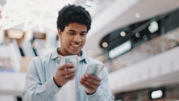 Feliz hombre africano emocionado contando dinero moneda dólares billetes efectivo en el interior disfrutando de éxito ganancia victoria lotería ganar biracial chico con sueldo finanzas facturas ahorro negocio beneficio — Vídeo de stock