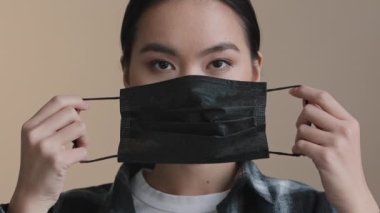 Ciddi Asyalı hasta bir kızın portresi. Yüzüne koruyucu siyah bir maske takıyor. Sağlığını koronavirüs bulaşıcı enfeksiyonundan koruyor.