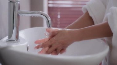 Yakın plan kadın elleri. Genç tanınmayan bir kadın modern banyo tedavisinde lavabonun yanında duruyor. Avuçlar temizleniyor, bakteriler temizleniyor, günlük hijyen, el bakımı, cilt bakımı, kozmetik bakım.