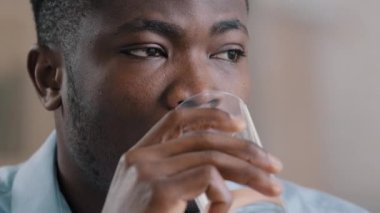 Yakın çekim Afrikalı milenyum adamı saf soğuk su bardağı iç sağlıklı sıvı sıcak alışkanlıktan muzdarip susuzluk çek Amerikalı düşünceli iş adamı düşüncelere daldı.