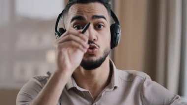Web kamerası görüntüsü genç İspanyol iş adamı tasarımcı blog operatörü kamera karşısında kulaklık takıyor projenin detaylarını açıkla görsel grafik erkek öğretmen eğitici web sitesi yaptı