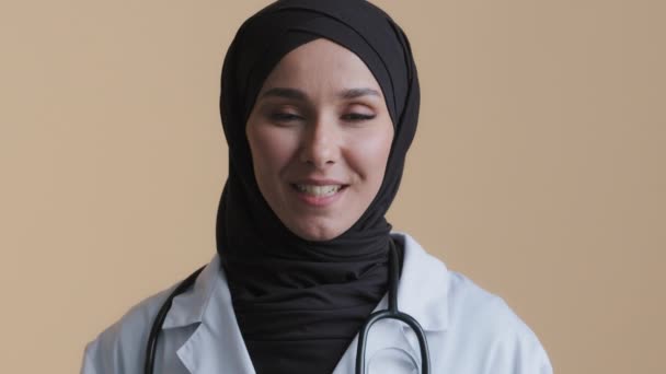 Ung muslimsk professionell kvinna kvinnlig läkare i hijab vit medicinsk uniform konsultation avlägsen patient tittar på kamera webbkamera virtuell videochatt ger avlägsna medicinska tjänster lär — Stockvideo