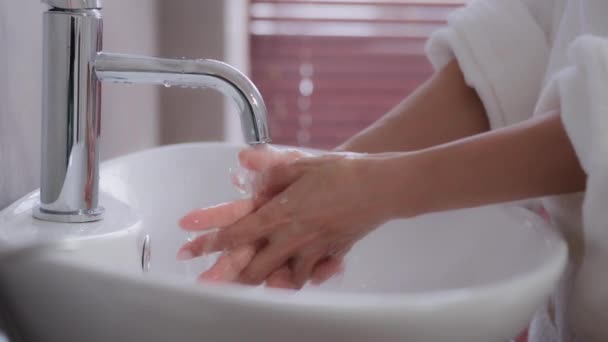 Close-up weibliche Hände junge unkenntliche Frau steht in der Nähe von Waschbecken im Bademantel in modernen Badezimmer Behandlung wäscht Handflächen reinigt Bakterien tägliche Routinehygiene Handhautpflege kosmetische Verfahren — Stockvideo