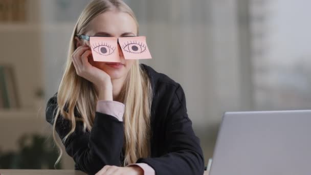 Tired sleepy caucasian woman with adhesive notes on eyes sticky notes on glasses. Lazy exhausted female sit at desk feel bored routine work. Overworked unmotivated lady with stickers on eyeglasses — ストック動画