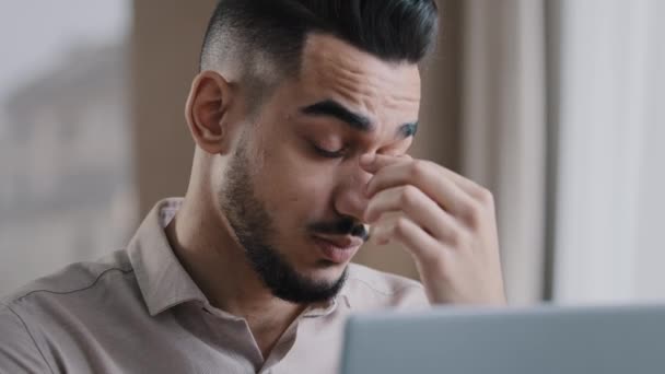 Εξαντλημένος νεαρός επιχειρηματίας της χιλιετίας καταπονημένος εργάτης που κάνει μασάζ σε στεγνά ευερέθιστα μάτια που αισθάνονται καταπόνηση μετά τη χρήση υπολογιστή κουρασμένος ισπανόφωνος άντρας που έχει πονοκέφαλο από τον πόνο κακό πρόβλημα όρασης — Αρχείο Βίντεο
