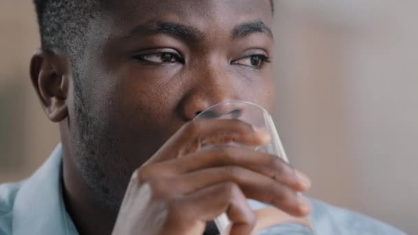 Közelkép fejlövés afrikai Y-generációs férfi inni tiszta hideg vizes pohár egészséges folyadék szenved meleg, hogy napi szokás hidrát szomjúság amerikai gondolkodó üzletember fickó elveszett gondolatok nézz félre — Stock videók