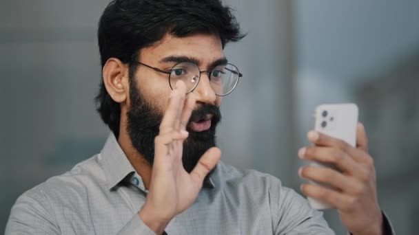 Árabe indiano jovem homem barbudo empresário bonito empresário segurar smartphone falando comunicação de vídeo on-line com o parceiro de negócios reunião virtual desfrutar de bate-papo usando aplicativo social saudação remota — Vídeo de Stock