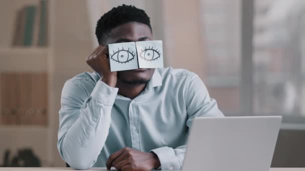 Somnolent drôle afro-américain gestionnaire de bureau homme d'affaires assis à la maison lieu de travail avec des notes collantes sur les yeux bande dessinée jeune travailleur fatigué a des problèmes de sommeil sieste au bureau porte des lunettes avec des autocollants — Video