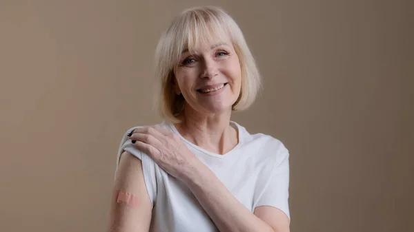 Infección por Coronavirus covid19 vacunación feliz mujer adulta adulta vacunada posando con yeso médico adhesivo en el brazo después de soporte de inyección antivirus contra la enfermedad pandémica — Foto de Stock