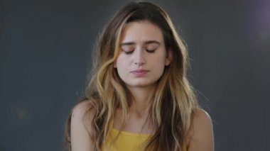 Üzgün, gücenmiş kadın yüzü, genç, güzel bayan model stres, üzüntü, üzüntü, hayal kırıklığına uğramış üzüntü, hüzün, stüdyonun gri arka planında tek başına duruyor.