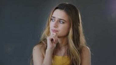 Blonde Millennial kızı tedirgin, korkmuş, stresli, düşünceli, beyaz kadın bayan, gri arka planda, stüdyonun sert çözümünde yalnız duruyor.