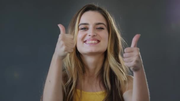 Kobieta studio portret na szarym tle uśmiechając się piękne zadowolone szczęśliwy kobieta model kobieta patrząc na aparat pokazuje dwa lubi kciuki w górę zatwierdzając wyrażając pozytywny gest dobry pomysł — Wideo stockowe