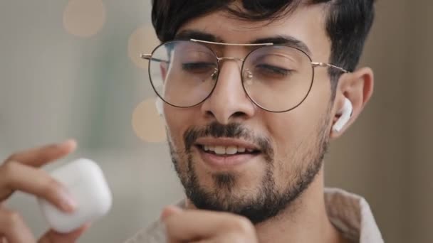 Primer plano macho cara feliz retrato árabe hispano indio hombre barbudo con gafas escuchando música con auriculares inalámbricos canta canción favorita disfrutando del sonido de audio en los movimientos de auriculares modernos — Vídeo de stock