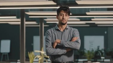 Kendine güvenen Hintli Arap işadamı, profesyonel işçi, kollarını çapraz bağlamış yakışıklı Arap yetişkin adam yöneticisiyle birlikte, kameraya bakıp, pozitif yüz ifadesiyle gülümsüyor.